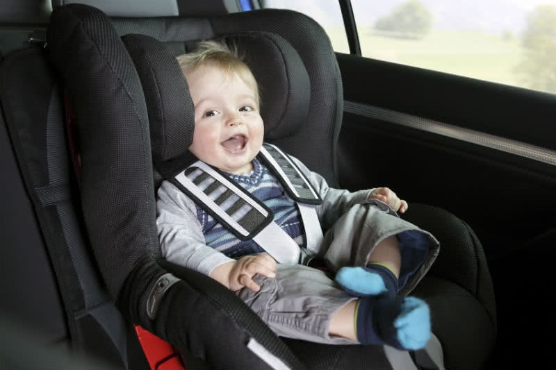 Fröhliches Baby im Kindersitz Baby im Kindersitz im Leasing Auto